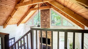 Un intérieur en bois avec une cheminée en pierre, de grandes fenêtres et un escalier.