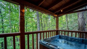 Une terrasse en bois avec un jacuzzi donnant sur une forêt.