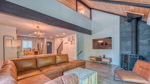 A spacious living area with a brown leather sofa, a wooden coffee table, and a fireplace. - Modern and Brand New, Pool, Camelback Ski Area, 2 showers (Tannersville)