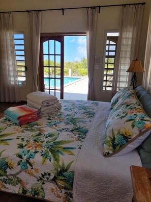 A bedroom with a bed, a view of a swimming pool, and a door leading outside.