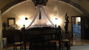 Un dormitorio con cama con dosel, una araña y una estatua.