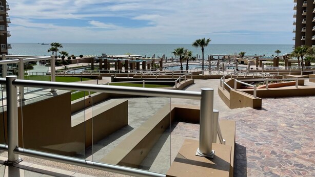 Un complexe hôtelier doté d’une piscine, de palmiers et offrant une vue sur l’océan.