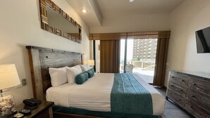 Une chambre d’hôtel avec un lit, des tables de chevet, une commode et une grande fenêtre donnant sur des immeubles.