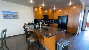Une cuisine moderne dotée d’un îlot central, de meubles en bois et d’un réfrigérateur noir.