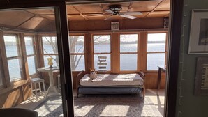 Une cabane avec un lit, une table et une vue sur un lac.