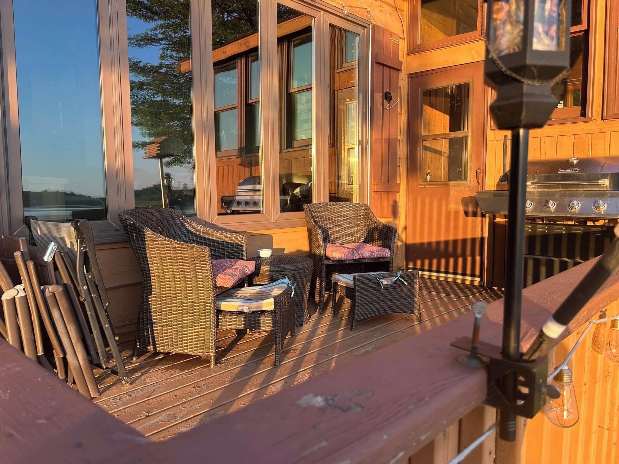 A wooden deck with wicker furniture and a grill.