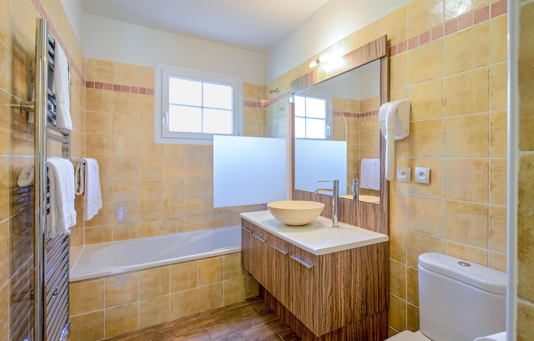 A bathroom with a bathtub, a sink with a large bowl, a toilet, and a mirror.