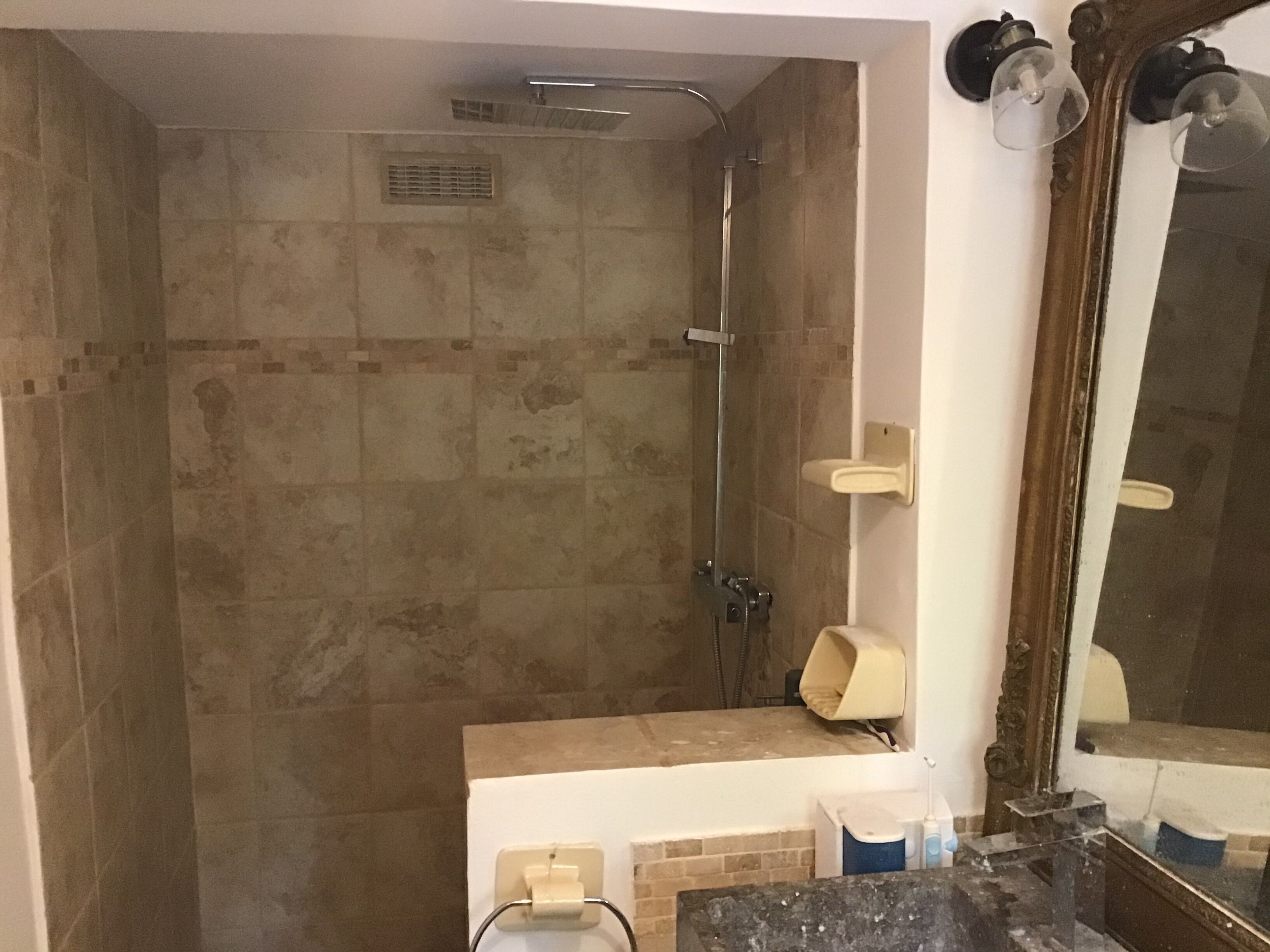 Un baño con ducha, lavamanos y espejo.