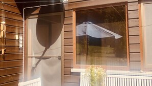 Une maison en bois avec une antenne parabolique, une porte-fenêtre coulissante et une terrasse avec une table et des chaises.