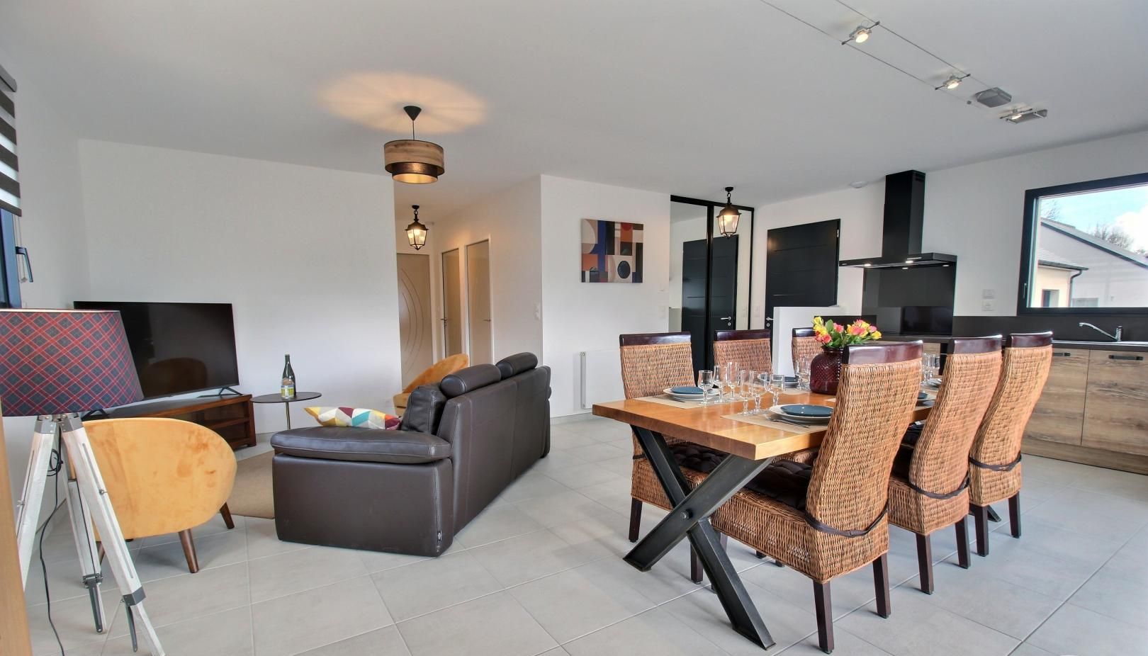 Un salon moderne comprenant un canapé, une table à manger avec des chaises, un téléviseur et une grande fenêtre.