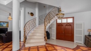 A grand staircase with ornate railings and a chandelier, leading to a wooden door. - Beautiful home in Rab (Rab)