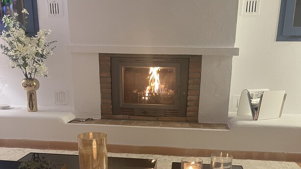 A fireplace with a fire, a vase with white flowers, and candles on a black tray. - VILLA WITH POOL 5 MINUTES FROM THE BEACH (TORREGUADIARO)
