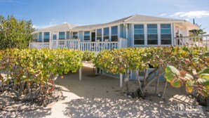 A beachfront property with a covered patio and a sandy beach area.