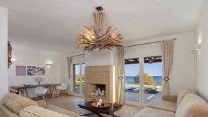 A spacious living room with a fireplace, comfortable seating, and a view of the sea. - FZIN Villa Sevil (Rhodes)
