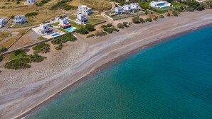 An aerial view of a coastal area with modern buildings, a beach, and clear blue waters. - FZIN Villa Sevil (Rhodes)