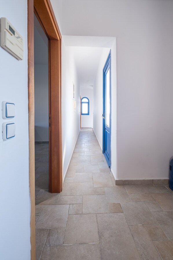 A hallway with a tiled floor, wooden door frames, and a blue door at the end. - FZIN Villa Sevil (Rhodes)