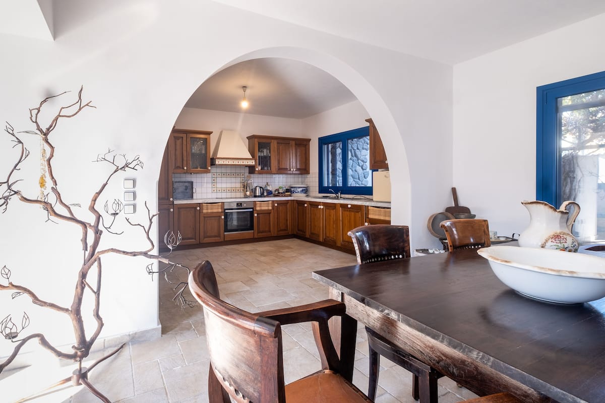 Eine moderne Küche mit Holdekor, einer zentralen Kochinsel und einem Essbereich mit einem dunklen Holztisch und Stühlen.