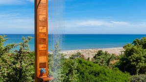 A wooden showerhead with water flowing into the sea, surrounded by greenery and a clear blue sky. - FZIN Villa Sevil (Rhodes)