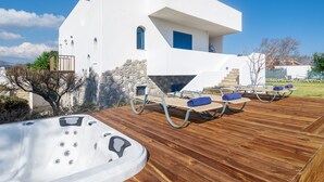 A modern white house with a wooden deck, outdoor seating, and a hot tub. - FZIN Villa Sevil (Rhodes)