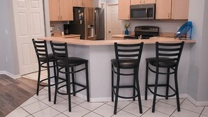 Une cuisine équipée d’un coin bar, comprenant un réfrigérateur, un four à micro-ondes et une cuisinière.