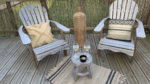 A wooden deck with two Adirondack chairs, a woven basket, and a small table with glasses and a bowl. - La Bigourdane (Gerde)