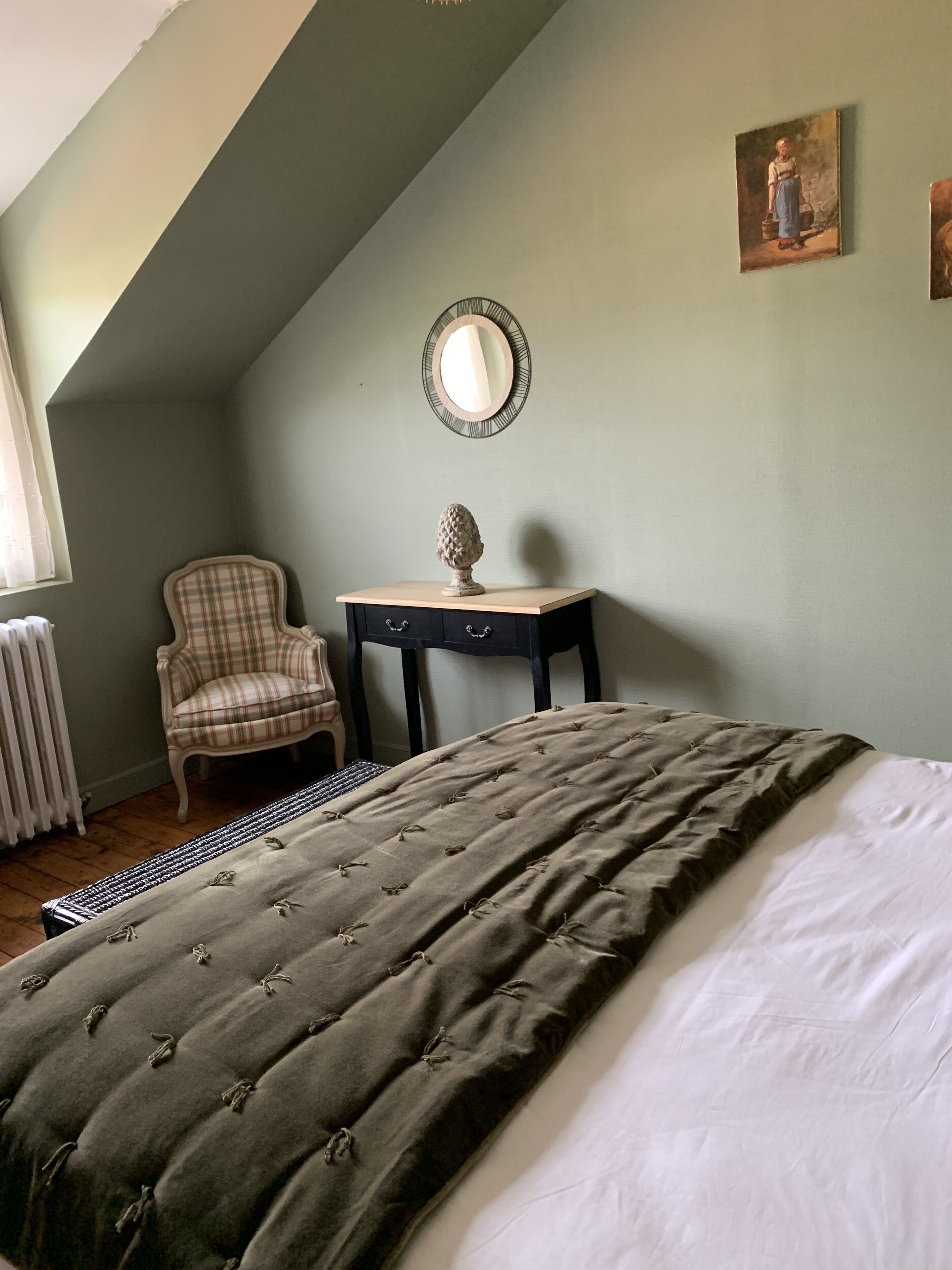 Ein Schlafzimmer mit einem Bett, einem Sessel, einem Schreibtisch und einem Bild an der Wand.