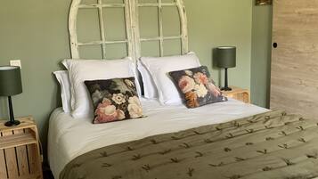 A bed with a wooden headboard, white bedding, and floral pillows. There are two bedside tables with lamps.