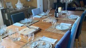 A dining room with a long wooden table set for a meal, surrounded by blue upholstered chairs. - La Bigourdane (Gerde)