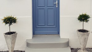 A blue door with a keyhole, flanked by two potted plants, and a sign with the letter 'B' above it. - La Bigourdane (Gerde)
