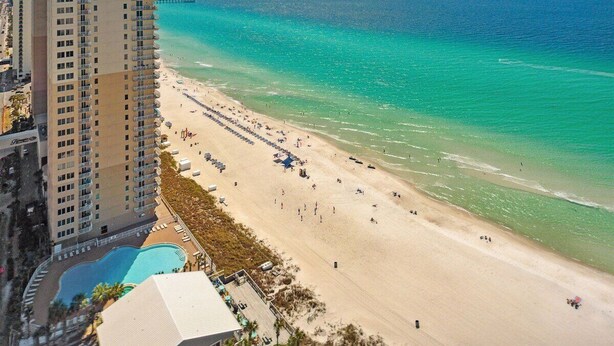 Ein Hochhaus-Hotel mit Blick auf den Strand, einem Pool und einer langen Sandküste.
