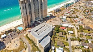 Ein Hochhaus-Hotel mit mehreren Etagen, einem Parkplatz und Blick auf den Strand.