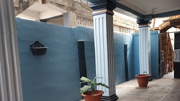 Zona exterior coberta amb parets blaves, plantes en testos i un paviment de rajoles.