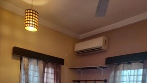Habitació amb un sòl estampat, un llit amb roba de llit estriada, una làmpada penjant, un aparell d'aire condicionat i un calefactor fixat a la paret.