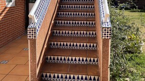 A staircase with blue and white patterned tiles, leading to a covered area with a fan and a window. - Annas Garden (Torrevieja)
