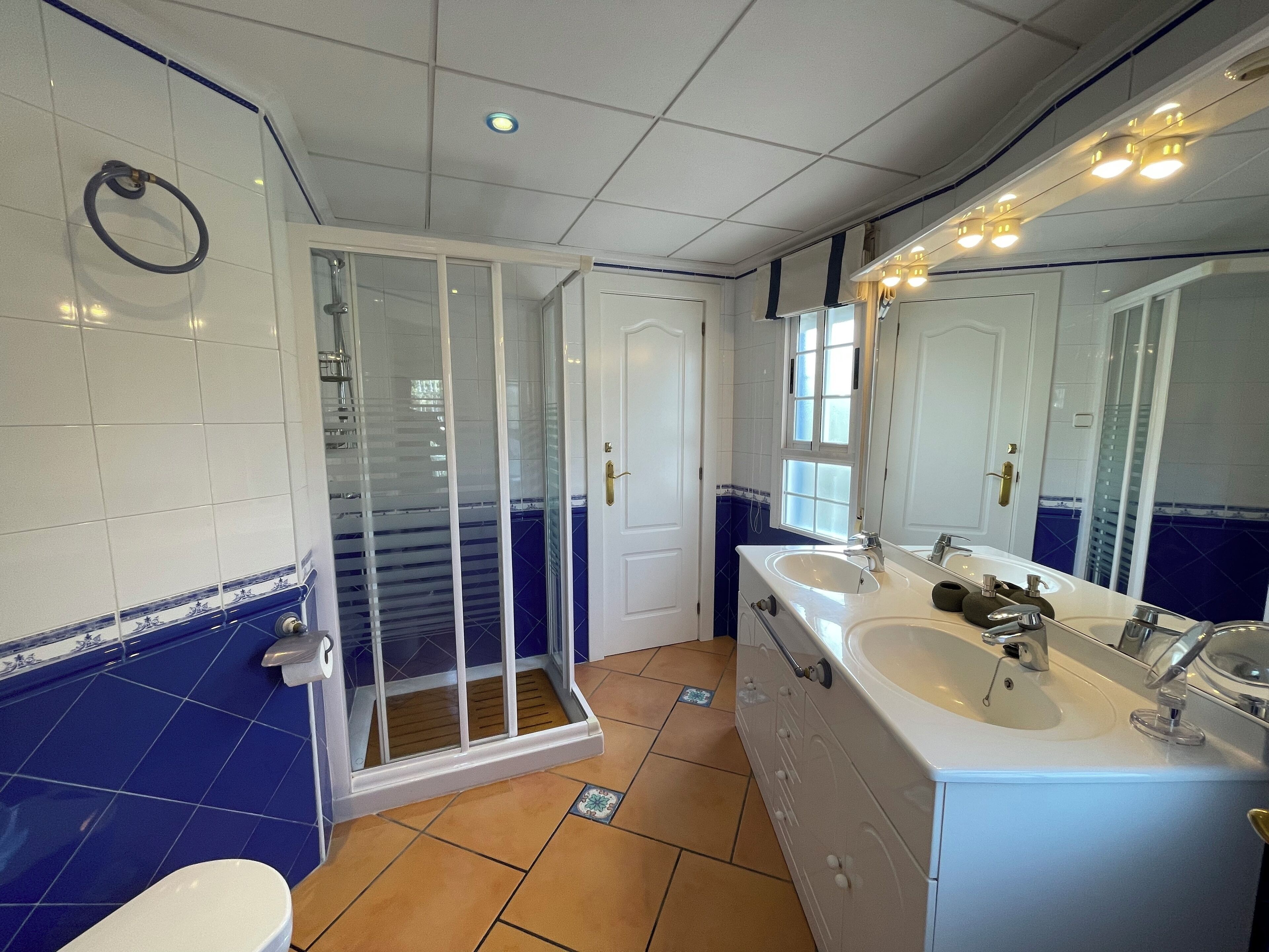 A bathroom with a shower, two sinks, and a large mirror.