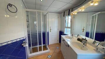A bathroom with a shower, two sinks, and a large mirror.