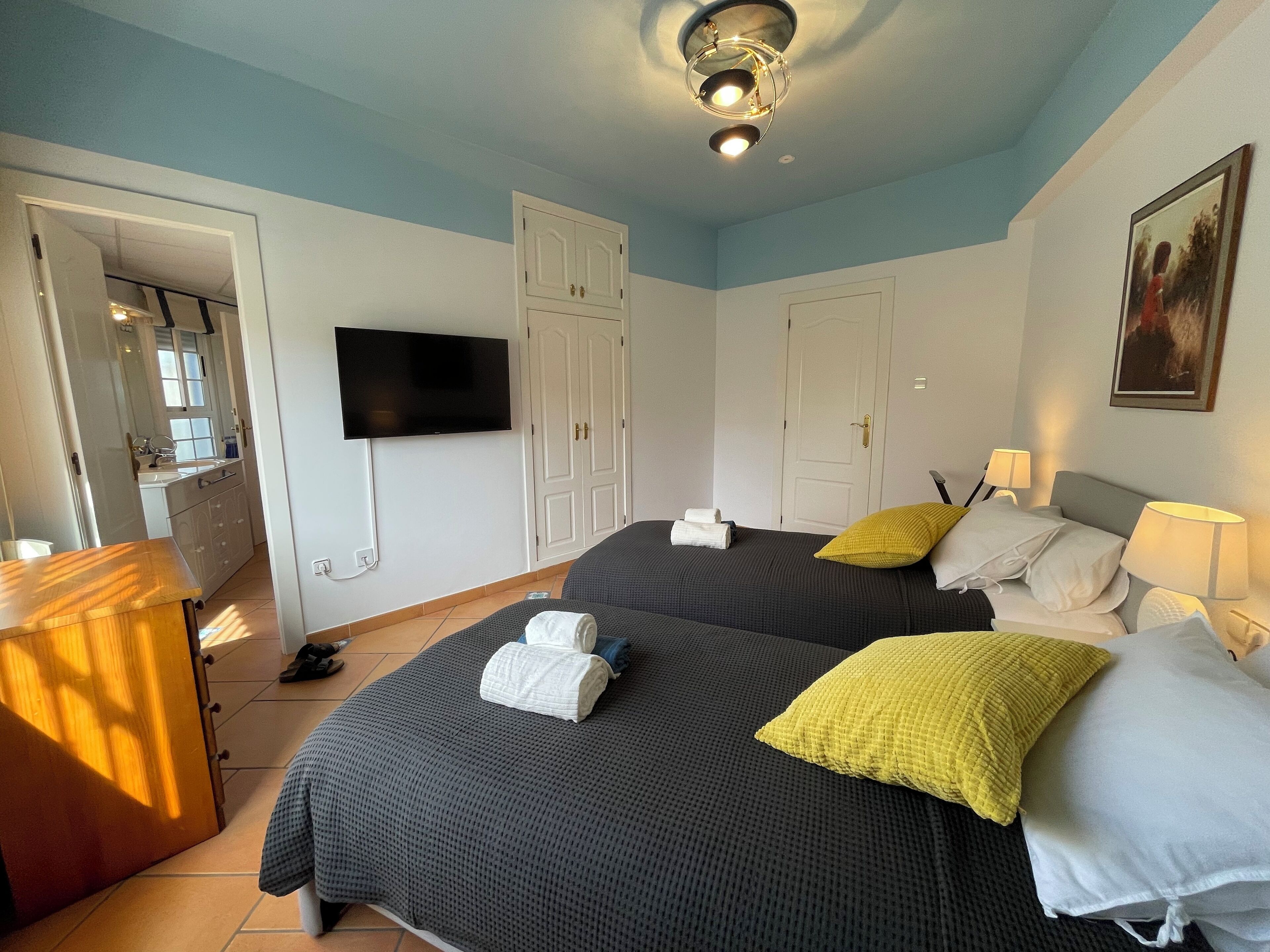 A hotel room with two beds, a TV, and a desk with a chair.