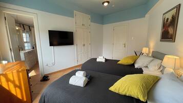 A hotel room with two beds, a TV, and a desk with a chair.
