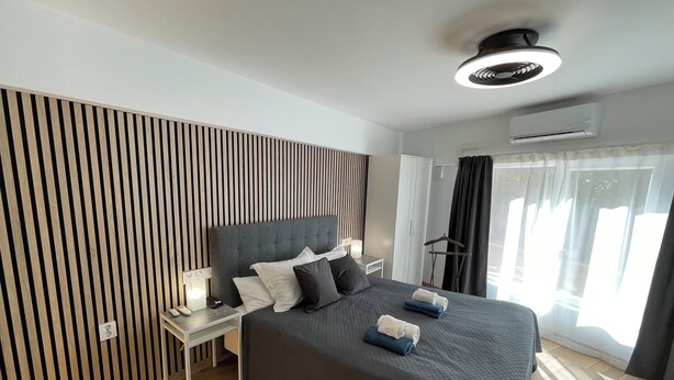 A modern hotel room with a large bed, a bedside table with a lamp, a wardrobe, and a ceiling fan. - Annas Garden (Torrevieja)