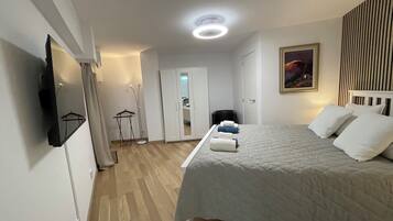 Un dormitorio con cama, armario, espejo, un cuadro y una lámpara en el techo.