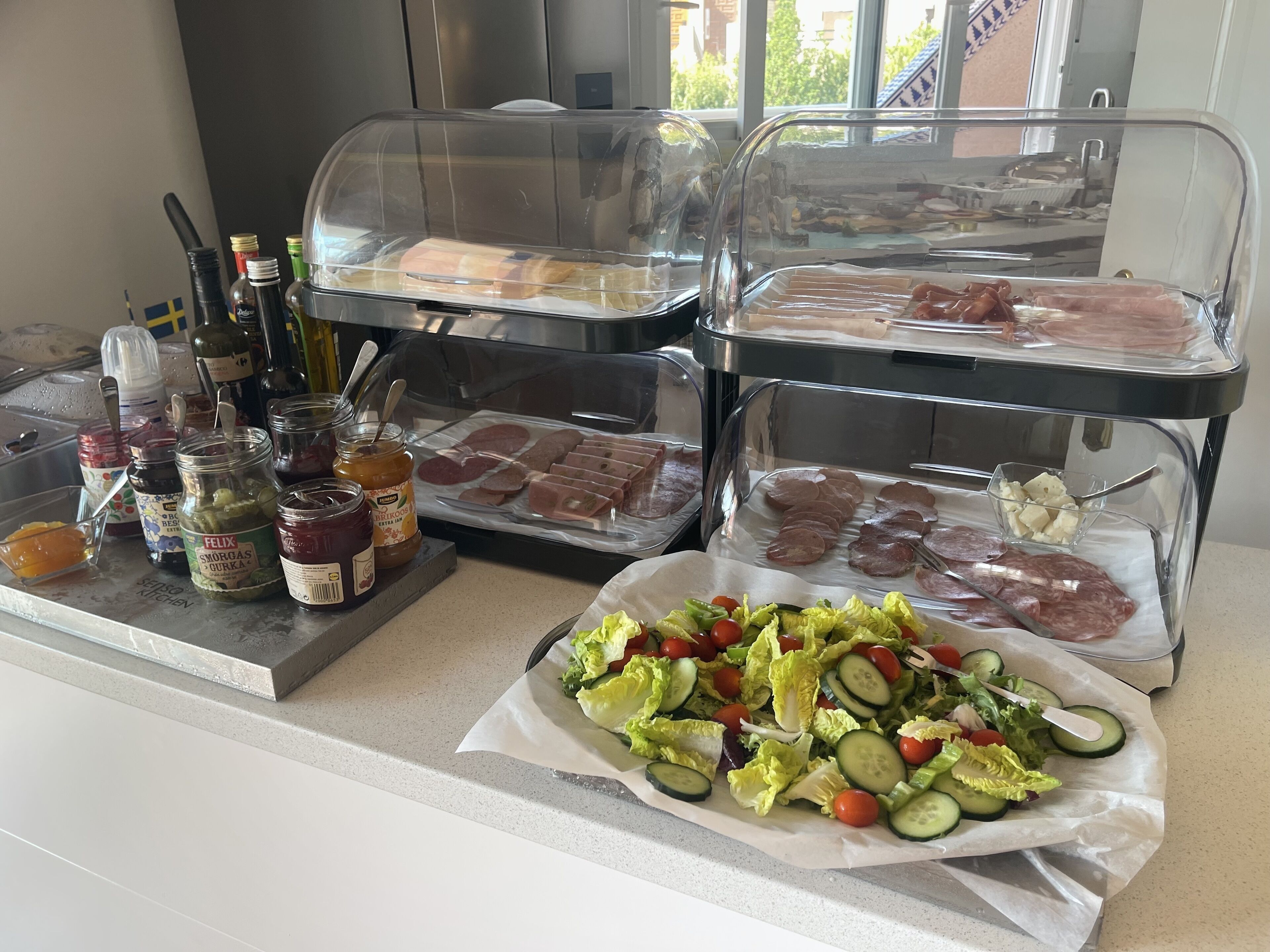 A buffet with various food options including meats, cheeses, and a salad.