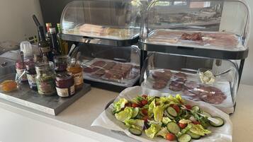 A buffet with various food options including meats, cheeses, and a salad.
