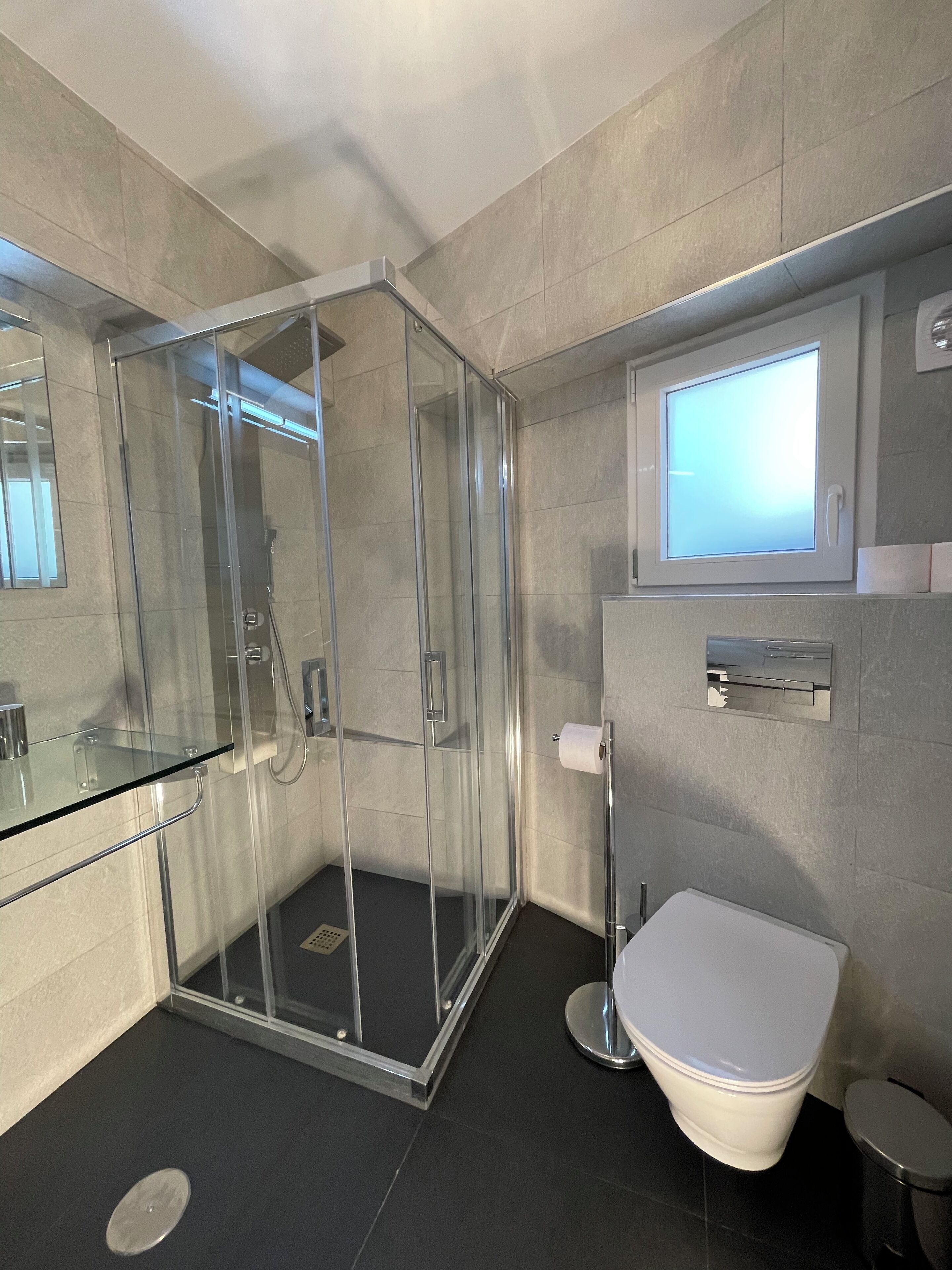 Un bagno moderno con doccia vetrata, un water e uno specchio.