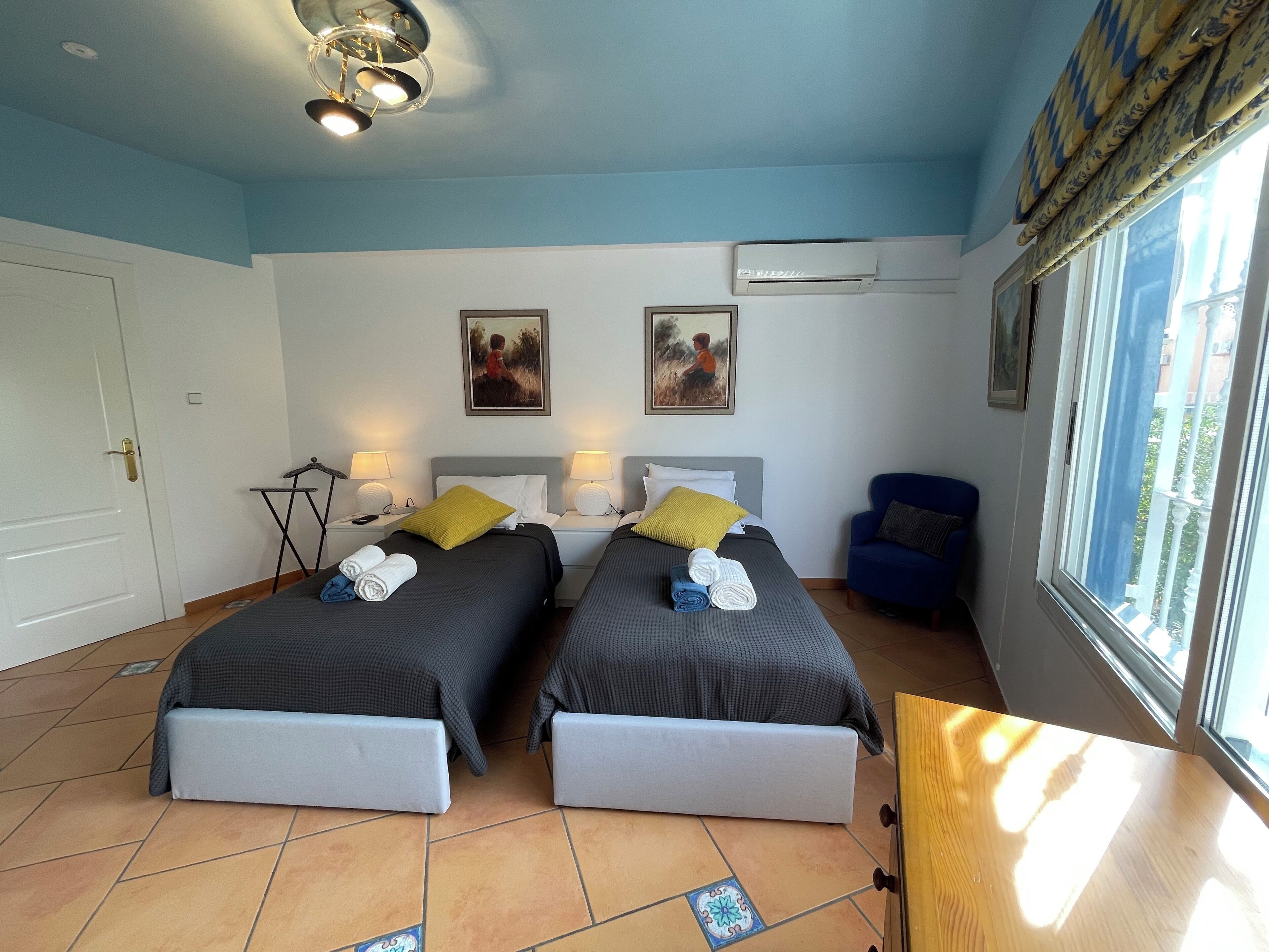 Una habitación de hotel con dos camas, una mesita, una silla y una ventana con vistas.