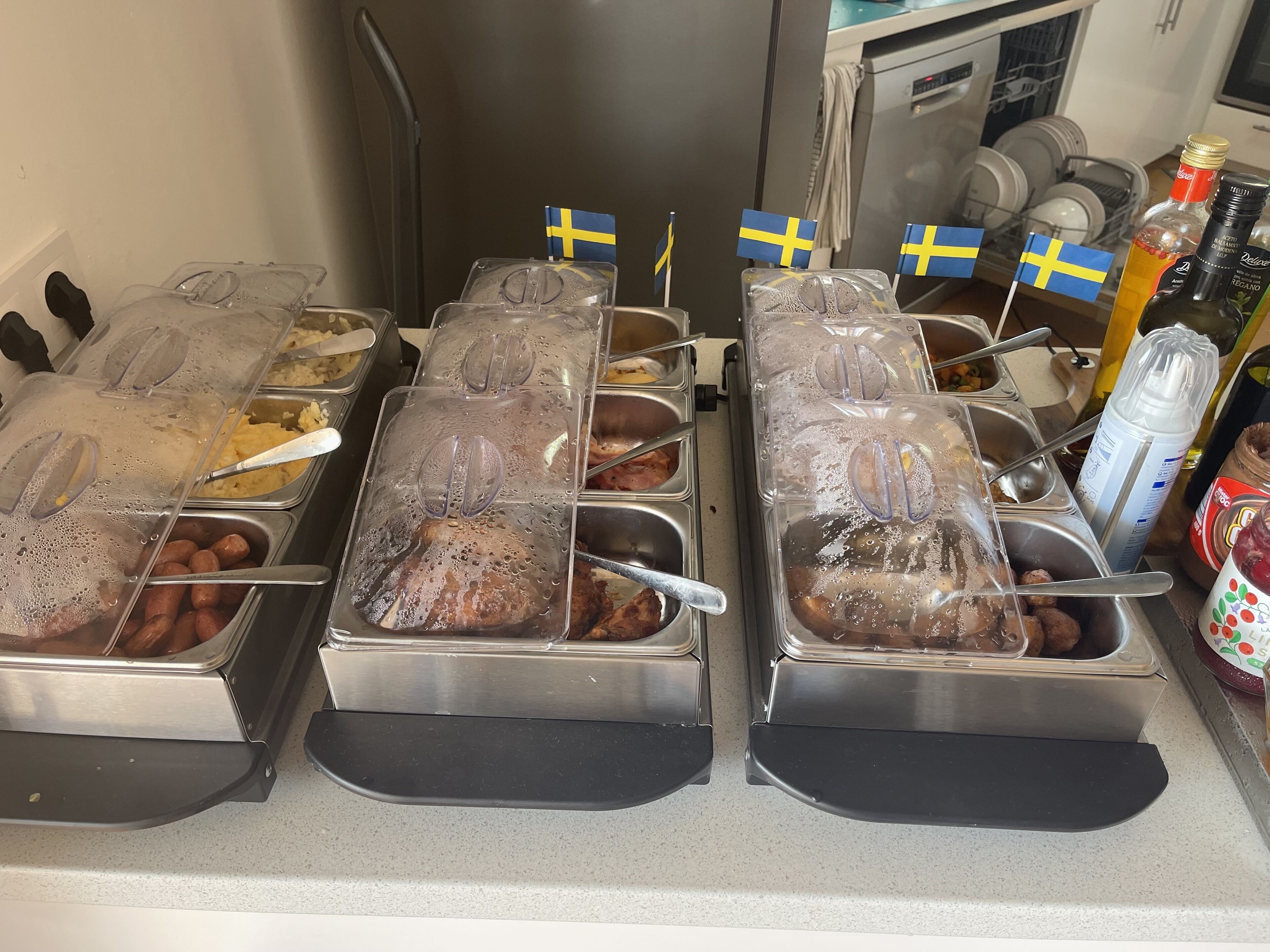 Einbufett mit verschiedenen Speisen, darunter Würstchen, Fleisch und ein Kuchen, jeweils mit schwedischer Flagge.