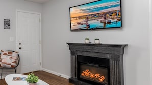 A living room with a fireplace, a flat-screen TV mounted above it, and a door with a sign. - Starved Rock & Ottawa Retreat Amazing Getaway Home (Ottawa)