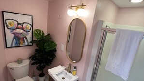 Un baño con inodoro, lavamanos, espejo y ducha.