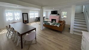 Un salón amplio con comedor, chimenea y escalera.