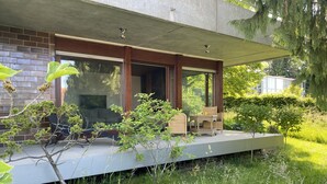 Een modern huis met een overdekte veranda, zitplaatsen buiten en een tuin.