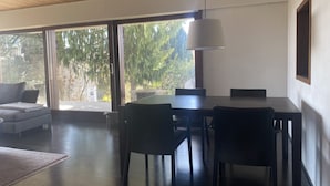 Een moderne eetruimte met een houten plafond, grote ramen en een tafel met stoelen.